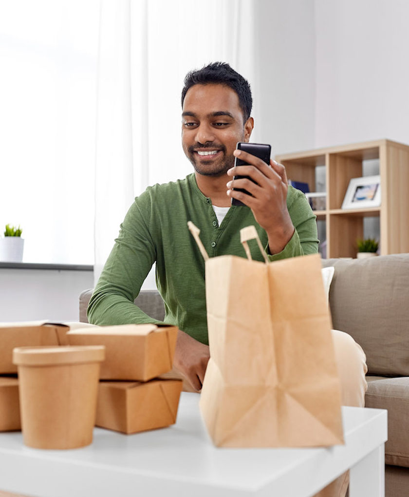 Man checking phone while looking at paper bags.