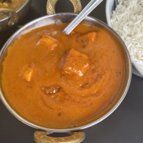 A bowl of curry and rice served with a spoon.